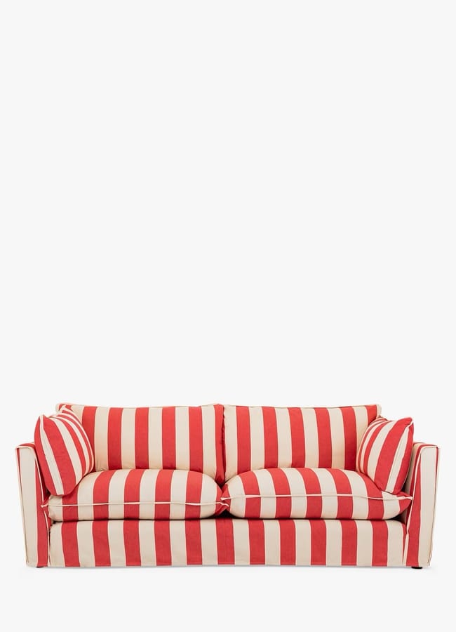 A red and white striped sofa with two matching round cushions, set against a plain white background—a statement piece reminiscent of the bold, vibrant style often found in maximalist hotels.