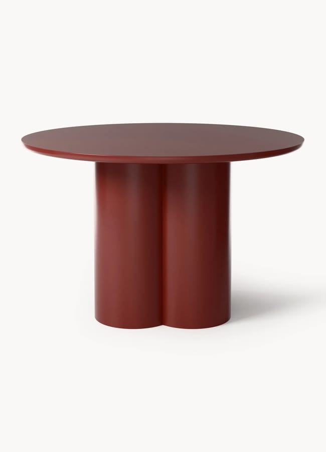 A round, dark red table with a thick tabletop and a unique base made of three cylindrical columns joined together—an eye-catching piece that would feel right at home in the vibrant interiors of maximalist hotels. The background is plain white.
