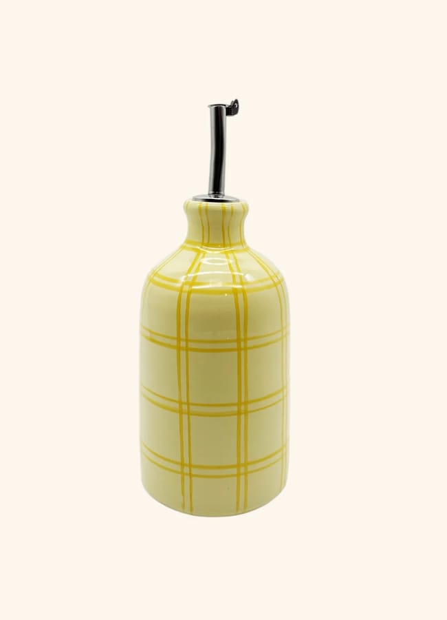A ceramic bottle with a yellow check pattern and a metal spout, perfect for dispensing olive oil during salad season, set against a plain light background.