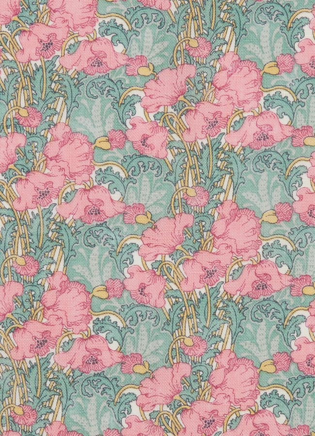 Patterned fabric showing clusters of pink flowers with yellow centres and green leaves on a light blue background, arranged in a dense, repeating Art Nouveau style—perfect for the bold, eclectic interiors often found in maximalist hotels.
