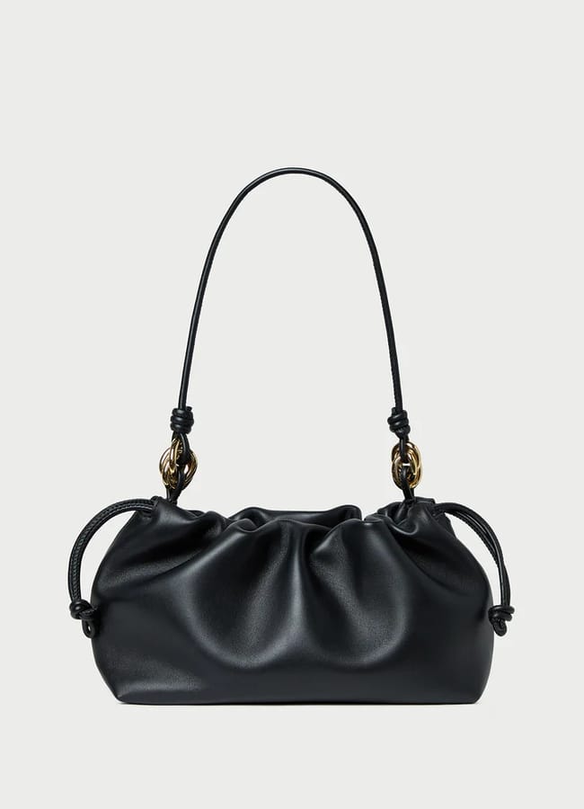 A small black leather handbag with a gathered, ruched design, gold hardware accents, and a thin shoulder strap—this high-end designer bag is displayed on a plain white background.