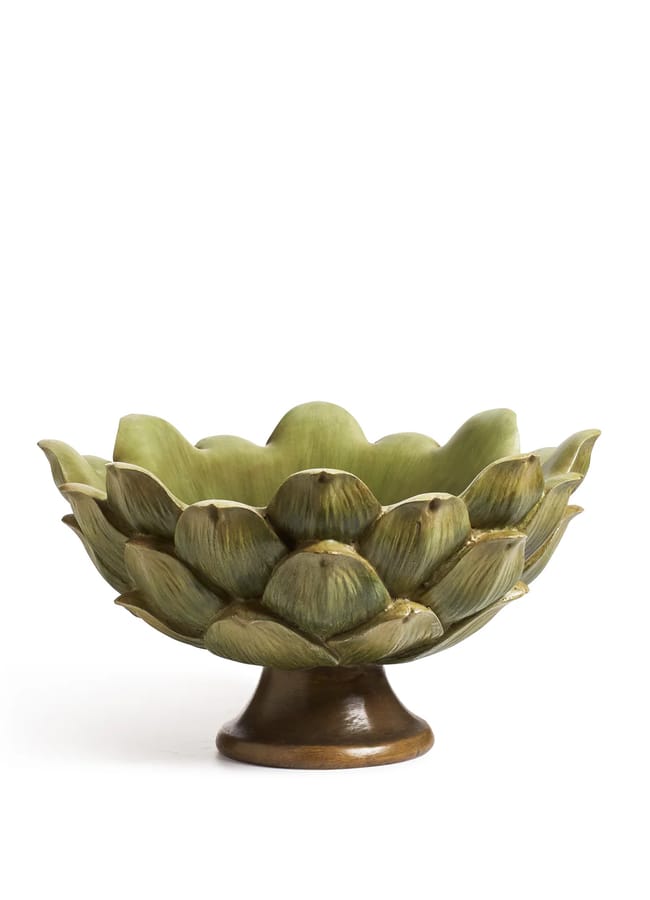 A ceramic bowl shaped like an artichoke with layered green leaves and a brown pedestal base, reminiscent of the bold decorative flair found in maximalist hotels, photographed against a white background.