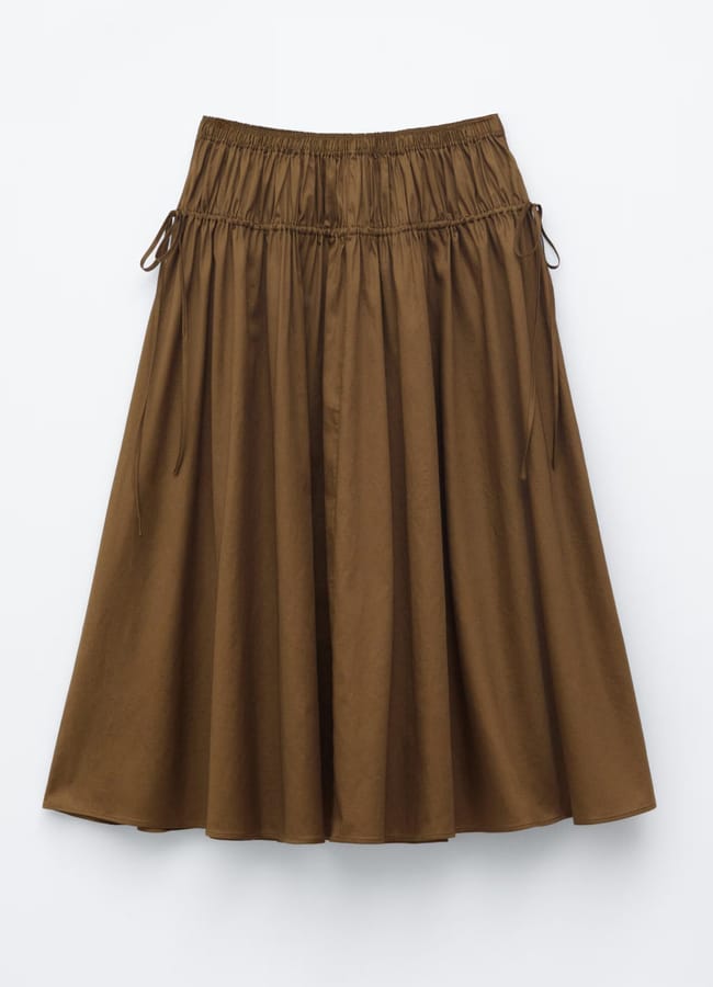 A brown, knee-length, A-line skirt inspired by high street fashion features an elasticated waistband and adjustable drawstrings on each side, displayed against a plain white background.
