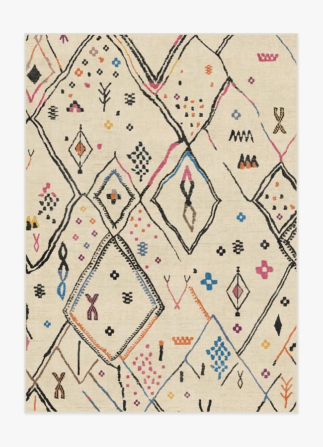 Beige rug with abstract, multicoloured geometric patterns, including diamonds, dots, and lines in black, blue, orange, pink, and yellow—bringing a playful, modern look inspired by the vibrant interiors often seen in maximalist hotels.