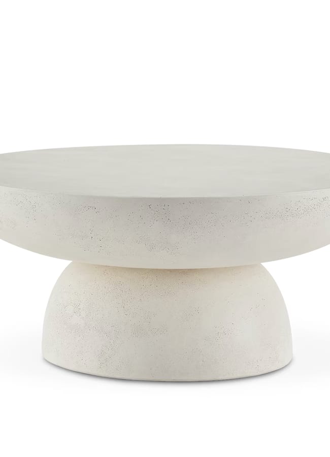A modern, round, white concrete table with a thick top and a rounded pedestal base. The table’s surface and base have a slightly textured finish. While the design is minimalist and contemporary, its bold presence can also serve as an eye-catching centrepiece in maximalist hotels.
