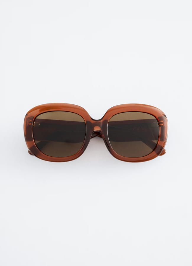 Brown, square-framed sunglasses with dark lenses are displayed against a plain white background, facing forward—an essential accessory for anyone wondering what to wear in Ibiza.