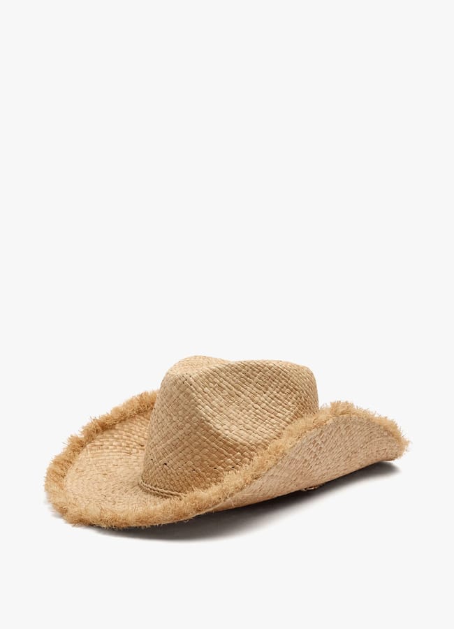A beige straw hat with a wide, floppy brim and frayed edges, placed on a white background—a perfect accessory for what to wear in Ibiza.