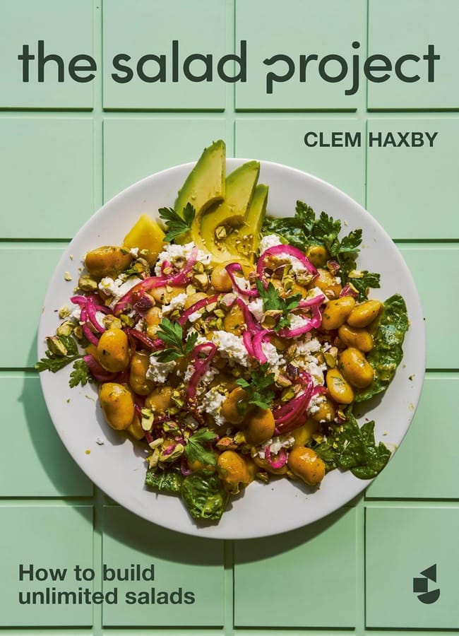 A cookbook cover titled The Salad Project by Clem Haxby features a vibrant salad with avocado, beans, greens, pickled onions, and cheese on a white plate against a mint green tiled background—perfect inspiration for salad season. Text reads How to build unlimited salads.