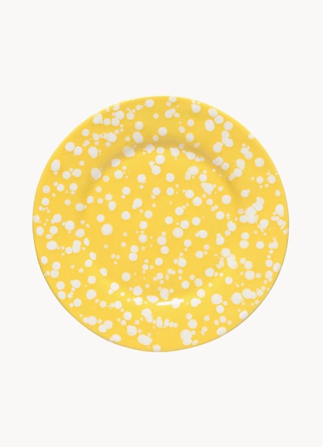 A round, yellow plate with a pattern of random white spots and splatters, perfect for brightening up your table this salad season. Set against a white background.