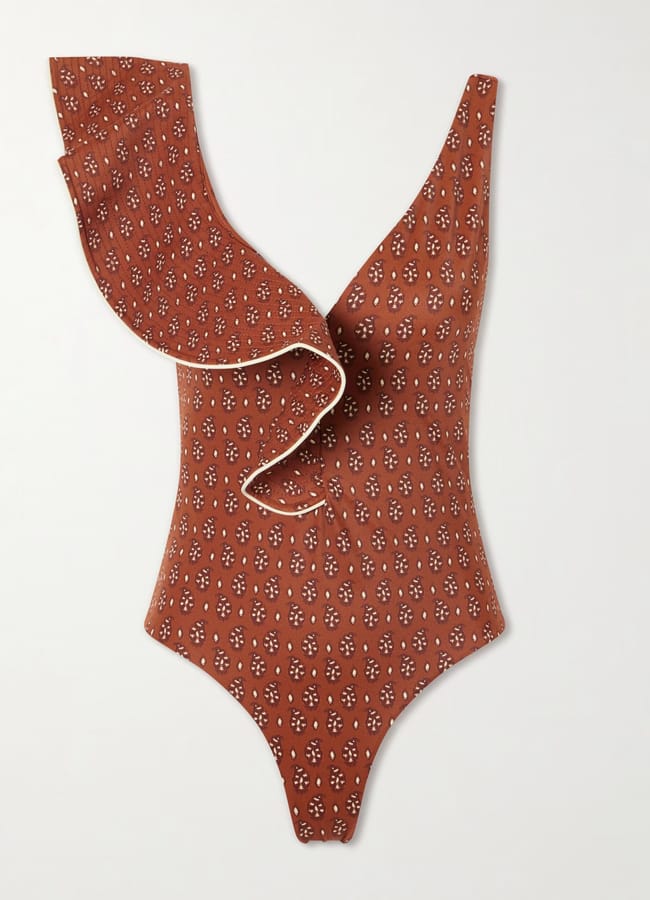 Pretty swimwear at its finest, this rust-coloured, one-shoulder swimming costume features a white floral pattern and a large frill detail across the chest and shoulder, laid flat on a white background.
