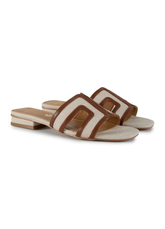 A pair of flat slide sandals with beige soles and wide, brown-trimmed fabric straps featuring cut-out designs—perfect for effortless holiday fashion or adding a chic touch to your last minute holiday looks.