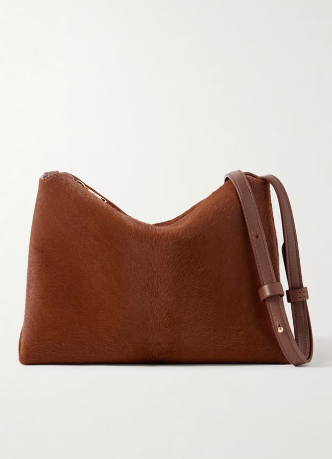A brown, rectangular crossbody bag with a smooth, soft texture and an adjustable leather strap, now featured in our summer sale, displayed against a plain white background.