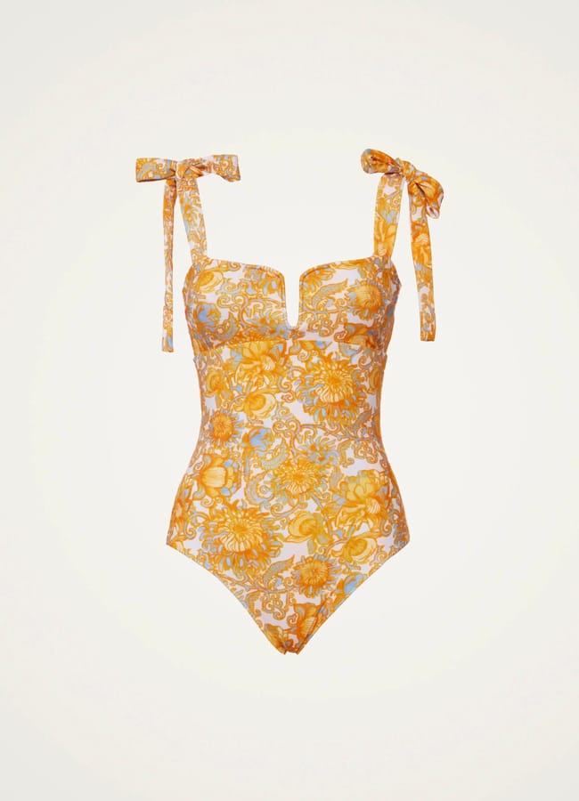 Pretty swimwear one-piece with yellow floral and sun motifs, featuring adjustable shoulder straps tied in bows, displayed on a plain white background.