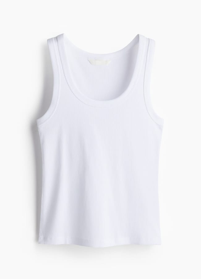 A white, sleeveless, ribbed vest with a scoop neckline is displayed against a plain white background—a style often seen on celeb couples who effortlessly blend comfort and trend.