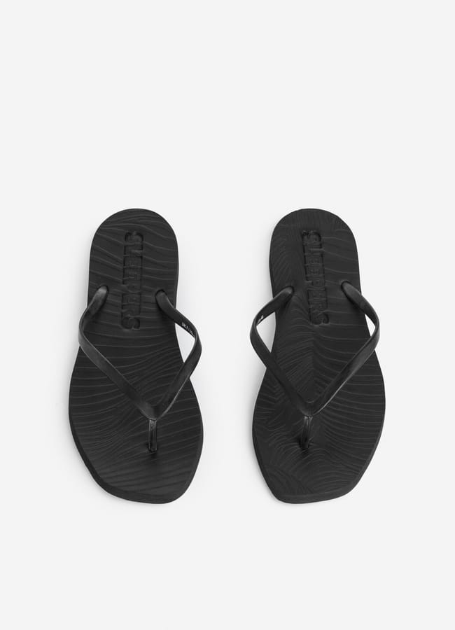 Pair of black flip-flops with textured soles seen from above on a plain white background. Perfect for embracing effortless holiday style, the brand name SANDALS is embossed on the upper part of each sandal.