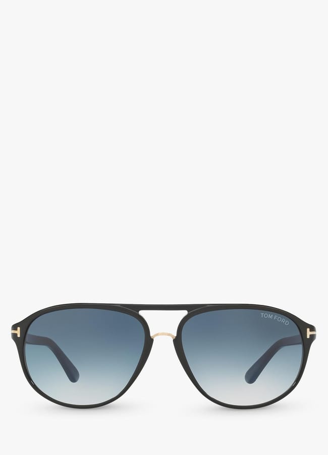 Black aviator-style sunglasses with blue gradient lenses—perfect for adding a touch of celebrity fashion to any look. The frames have a thin gold accent above the nose bridge and a small TOM FORD logo on the top right lens. The background is solid white.