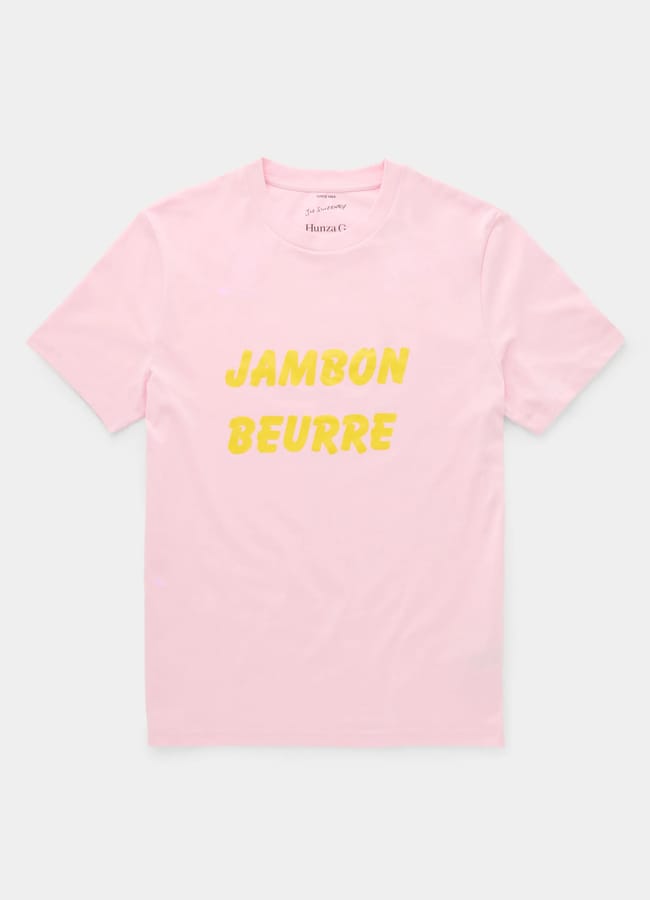A light pink short-sleeve t-shirt with the words JAMBON BEURRE printed in bold yellow letters on the front, perfect for fans of cool slogan tops.