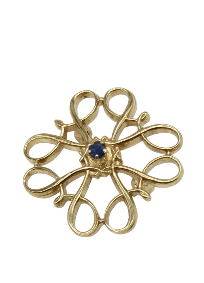A gold brooch with an intricate looping design, featuring a small blue gemstone set in the centre—a striking accessory perfectly aligned with autumn winter 2026 fashion trends.