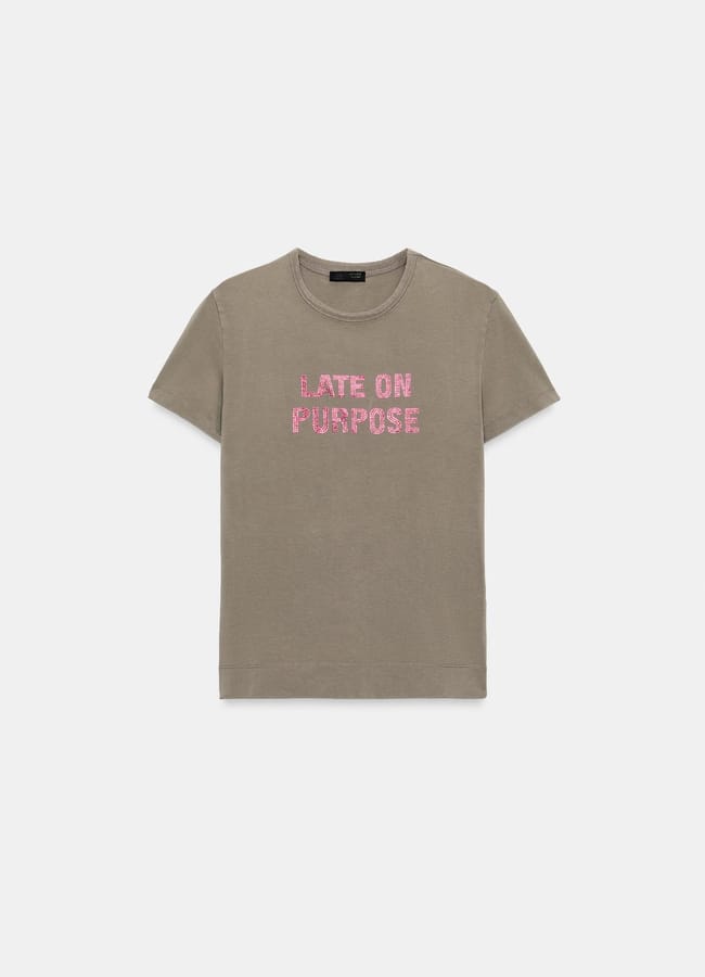 A plain khaki T-shirt with the phrase LATE ON PURPOSE written in bold pink letters across the chest—perfect for anyone who loves cool slogan tees.
