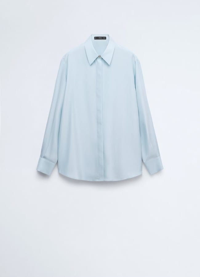 Light blue, long-sleeve button-up shirt with a collar, hanging against a plain white background. Inspired by minimalist high street brands, the shirt features a concealed button placket and cuffed sleeves.
