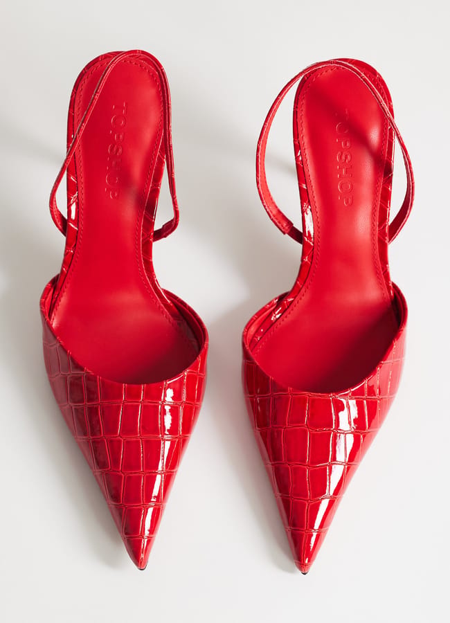 A pair of bright red, pointed-toe sexy heels with a crocodile texture, designed in a slingback style and viewed from above on a white background.