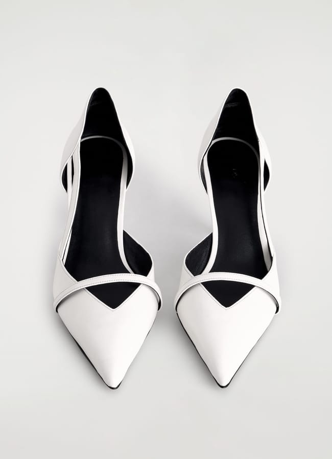 Pair of white pointed-toe sexy heels with black insoles and side cut-outs, photographed from above on a light background.