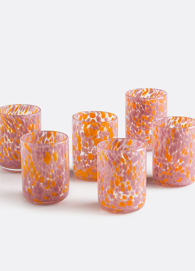 Six short drinking glasses with a pink and orange speckled pattern, showcasing unexpected colour combinations, are arranged in two rows on a plain white background.