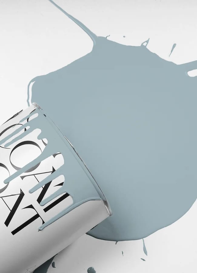 A silver paint tin tipped over on its side spills light blue paint onto a white surface, creating a large irregular puddle—an inspiring display of unexpected colour combinations.