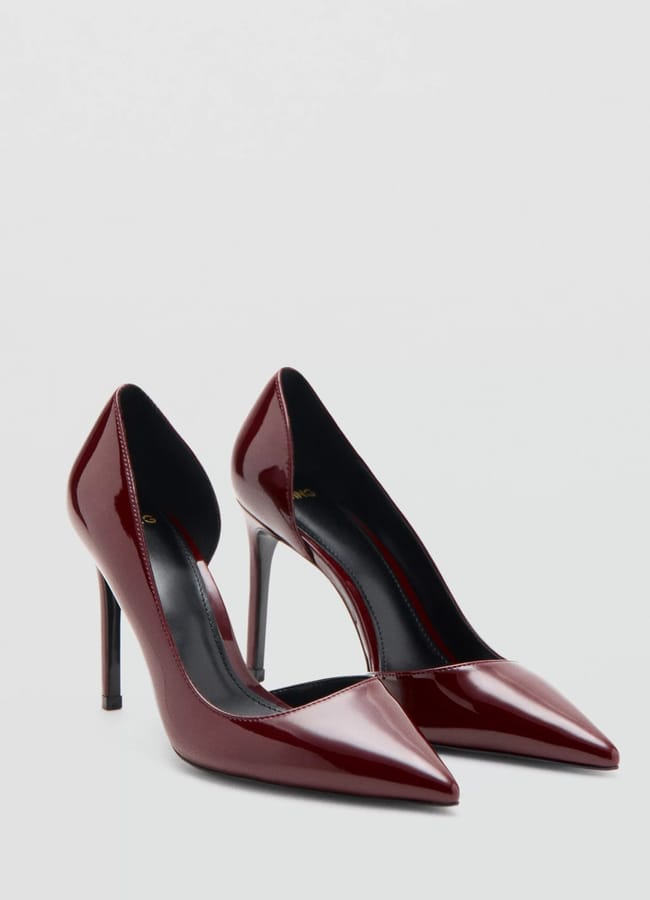 A pair of glossy dark red sexy heels with high, pointed toes are displayed against a plain light grey background.