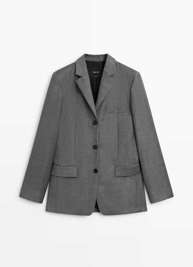 A single-breasted grey blazer with three black buttons, notched lapels, and two front flap pockets, displayed against a plain white background—an effortlessly chic piece inspired by minimalist high street brands.