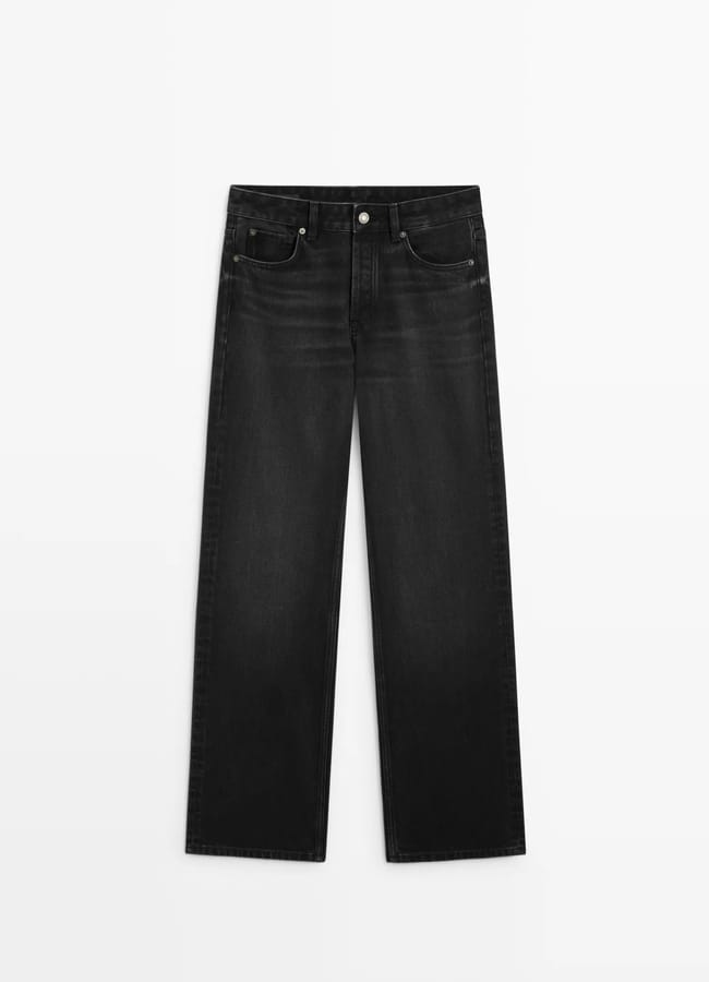 A pair of black straight-leg jeans with a classic five-pocket design, button and zip fastening, and subtle faded detailing—channelling the effortless style of minimalist high street brands—laid flat on a white background.