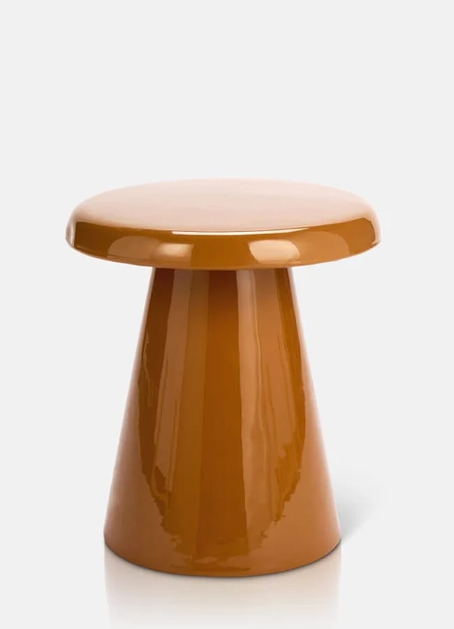 A glossy, brown, mushroom-shaped stool or side table with a round top and a conical base, this piece of caramel homeware is set against a plain white background.