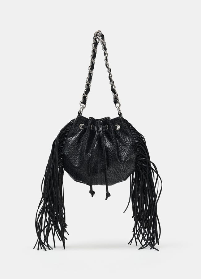 A black textured leather fringe handbag with a silver chain strap and drawstring fastening, displayed against a plain white background—perfect for cool girls seeking the ultimate autumn accessory.