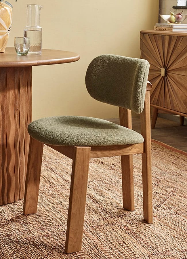 Dining chair with light wood legs and a textured olive green bouclé curved back and seat.