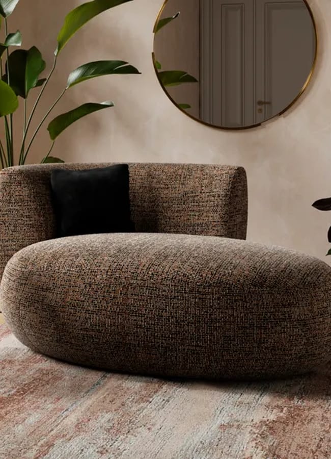 A rounded, low-profile armchair upholstered in a textured, brown bouclé patterned fabric with a single black accent cushion.
