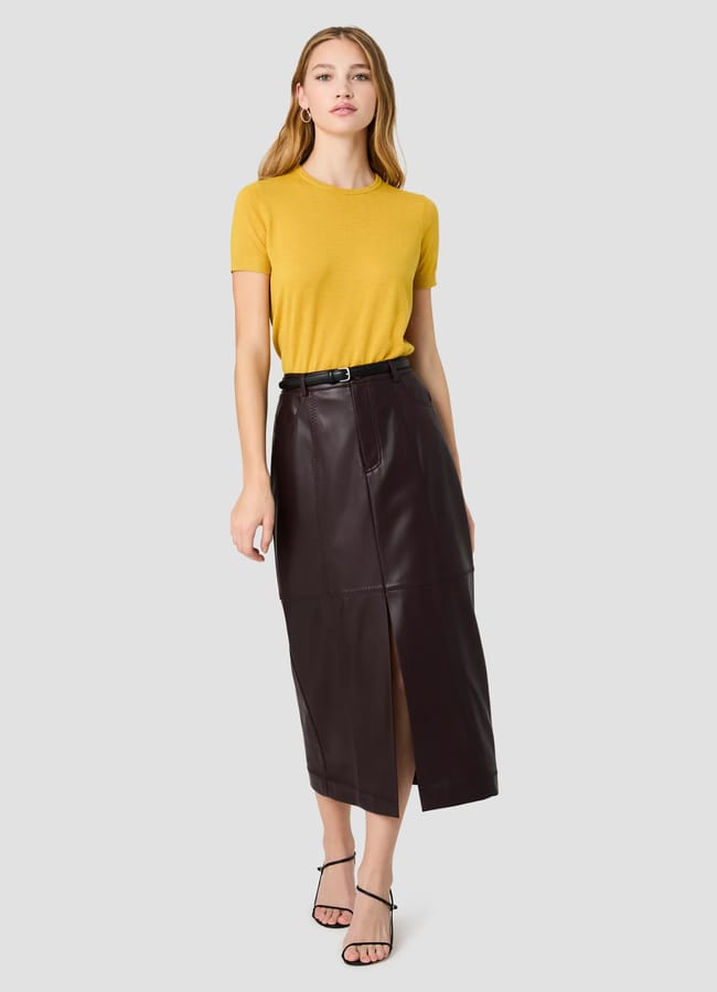 A model wears a mustard yellow short-sleeved top tucked into a dark brown pencil skirt with a front slit and a black belt, paired with black strappy sandals.