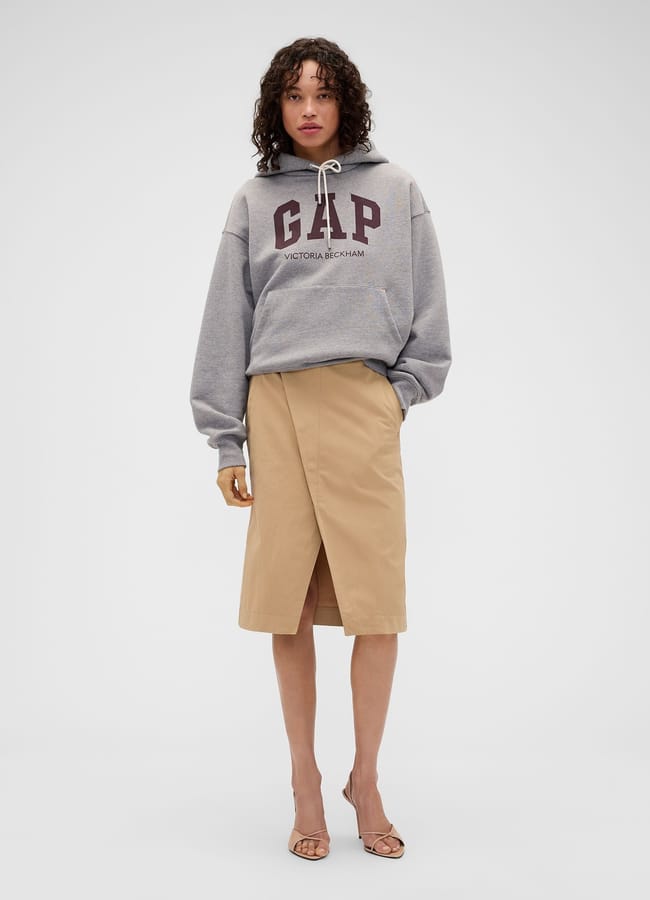 A person wearing a grey Gap Victoria Beckham hoodie and a tan wrap-style pencil skirt.