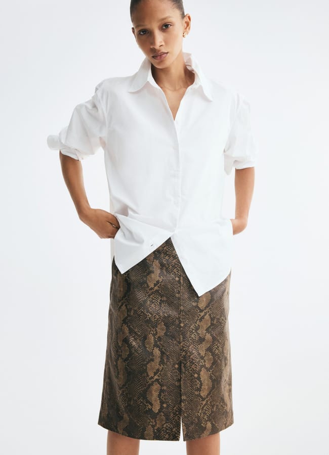 A model wearing a white button-down shirt and a brown snakeskin-print midi pencil skirt.