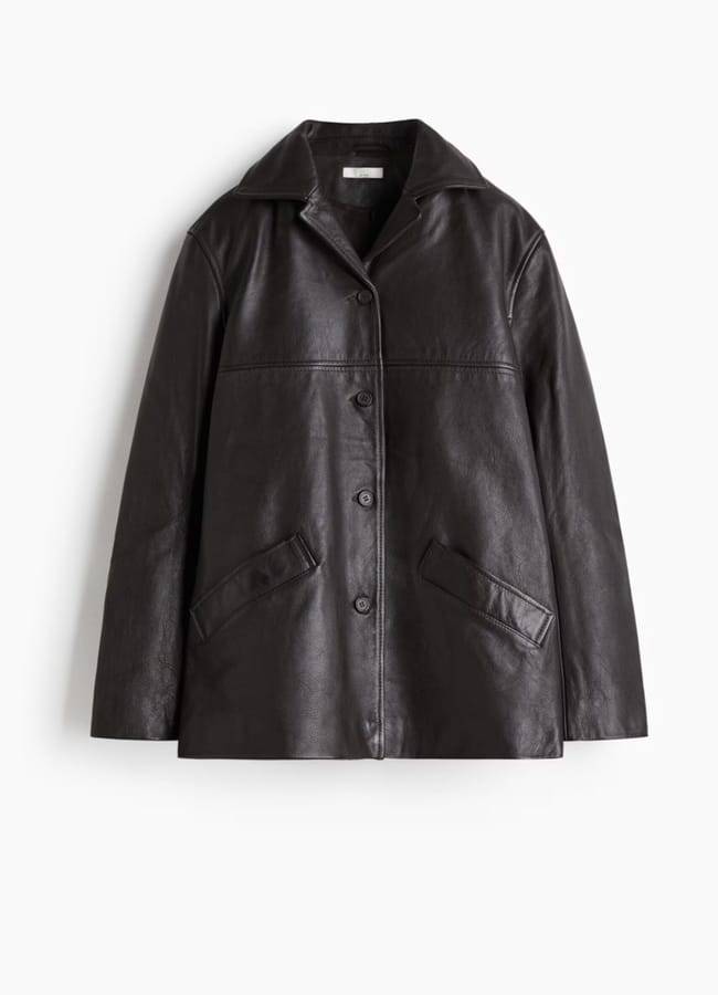 Black leather button-through jacket with a collar and two front welt pockets, one of the best women’s leather jackets for a classic look.