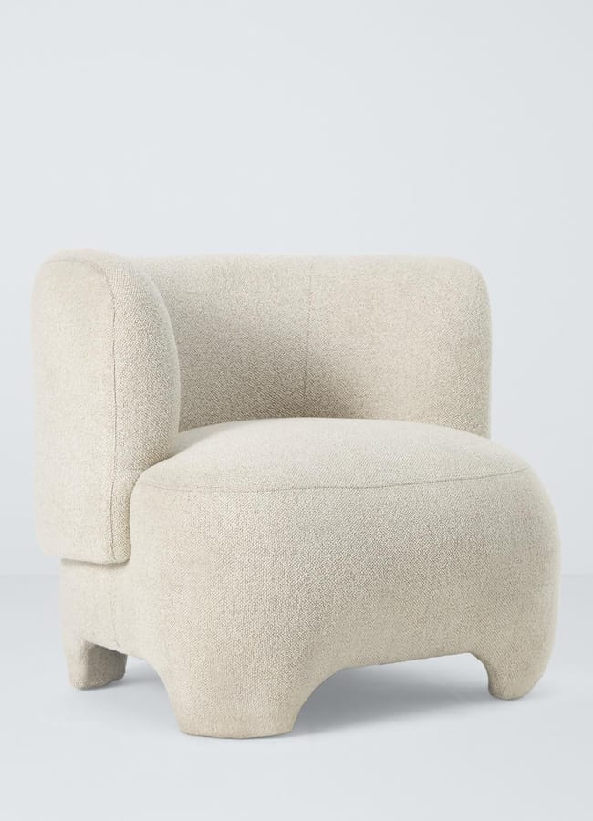 Off-white bouclé armchair with a curved back and low, block-style legs.