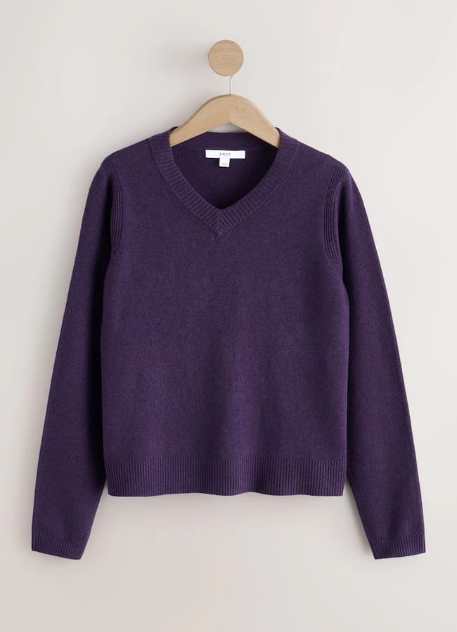 Purple V-neck jumper hanging on a wooden hanger.
