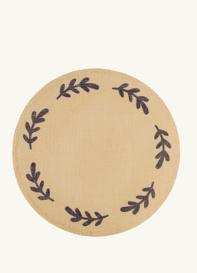 A circular beige coaster featuring a dark brown sprig pattern in a wreath design, perfect for autumn tablescape ideas.