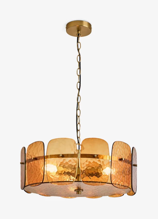 A circular Rockett St George pendant light featuring a brass frame and textured, amber-coloured glass panels.