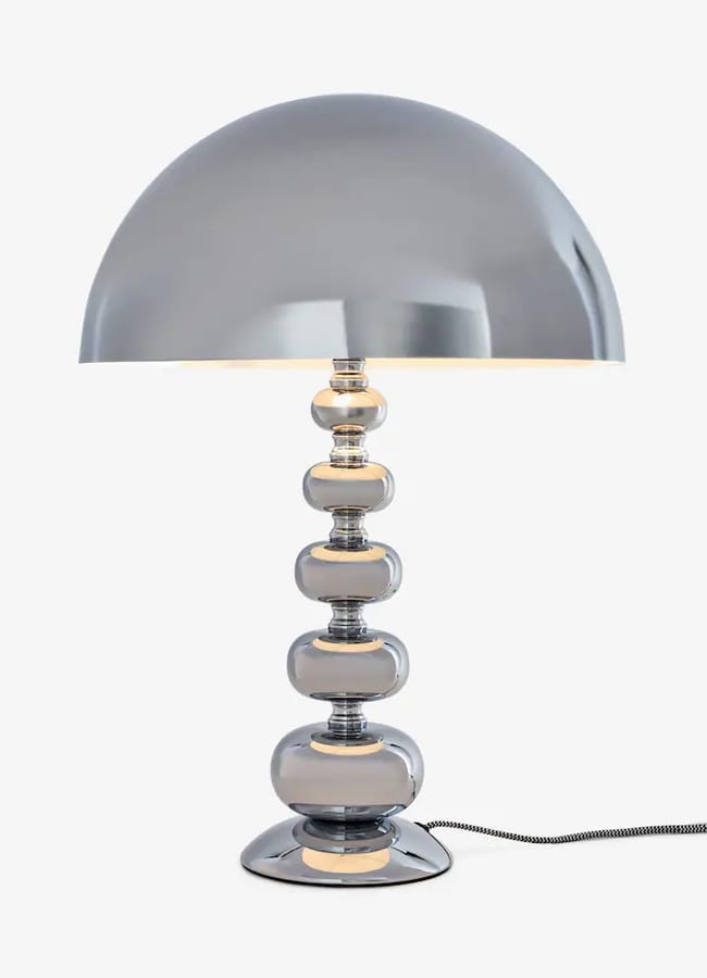 A Rockett St George table lamp with a wide, dome-shaped shade and a stem made of stacked, rounded metallic spheres.