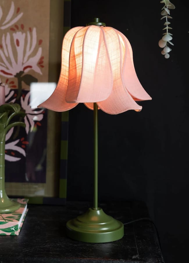 Rockett St George table lamp with a green base and a pale pink, fabric, petal-shaped lampshade.