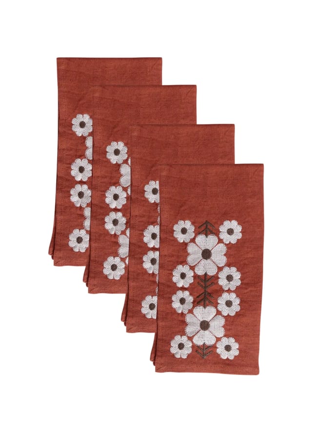 Four folded terracotta-coloured linen serviettes, each featuring a vertical row of white embroidered flowers, perfect for autumn tablescape ideas.