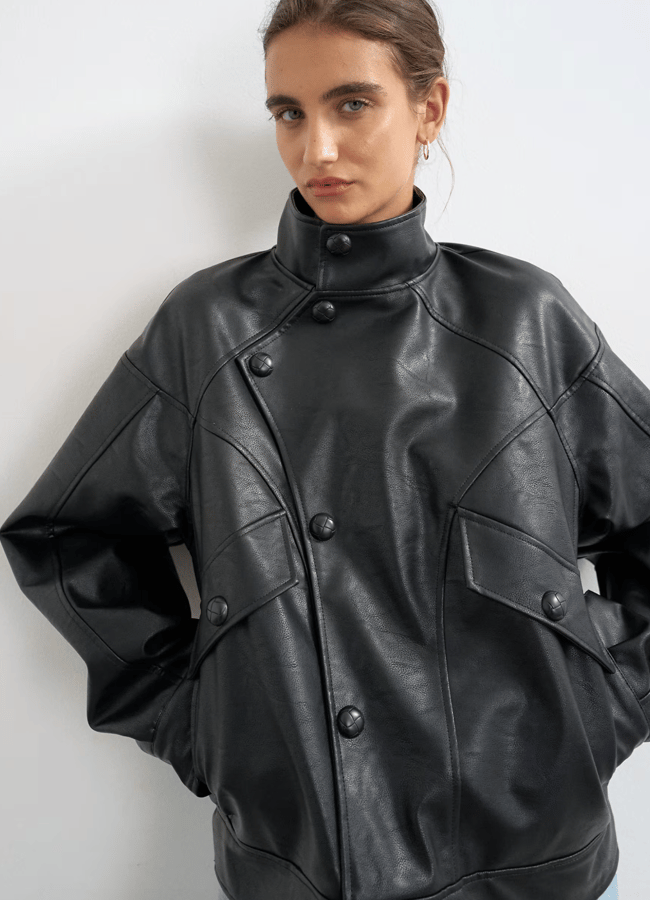 A person wearing one of the best women’s leather jackets: a black button-down style featuring a high collar and two large front pockets.