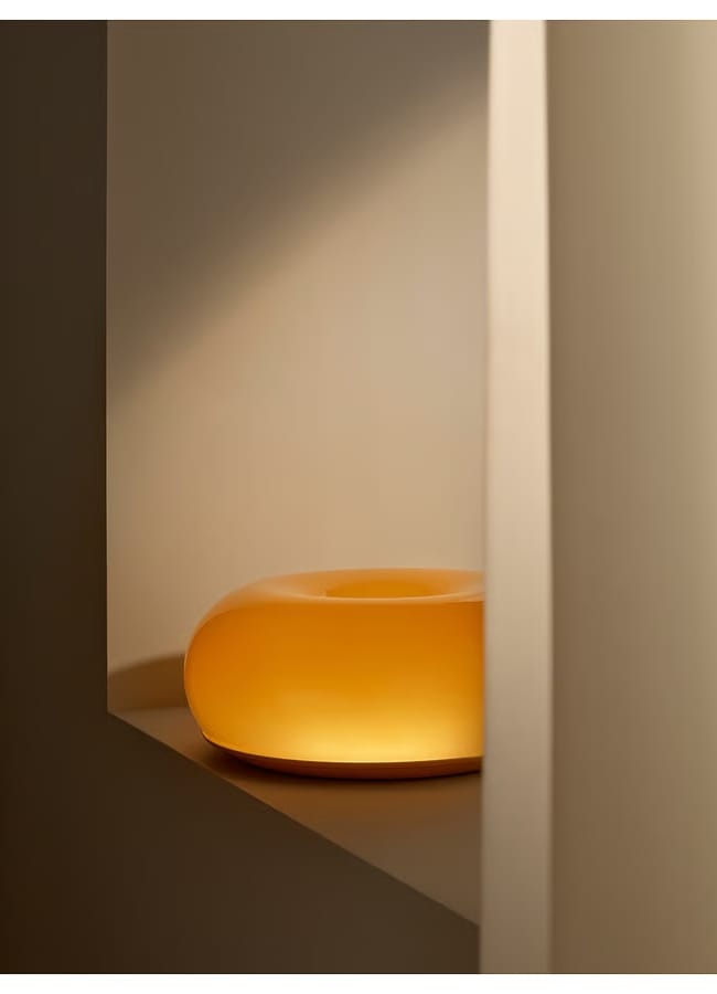 A glowing, doughnut-shaped orange lamp sitting on a ledge in a listening room.