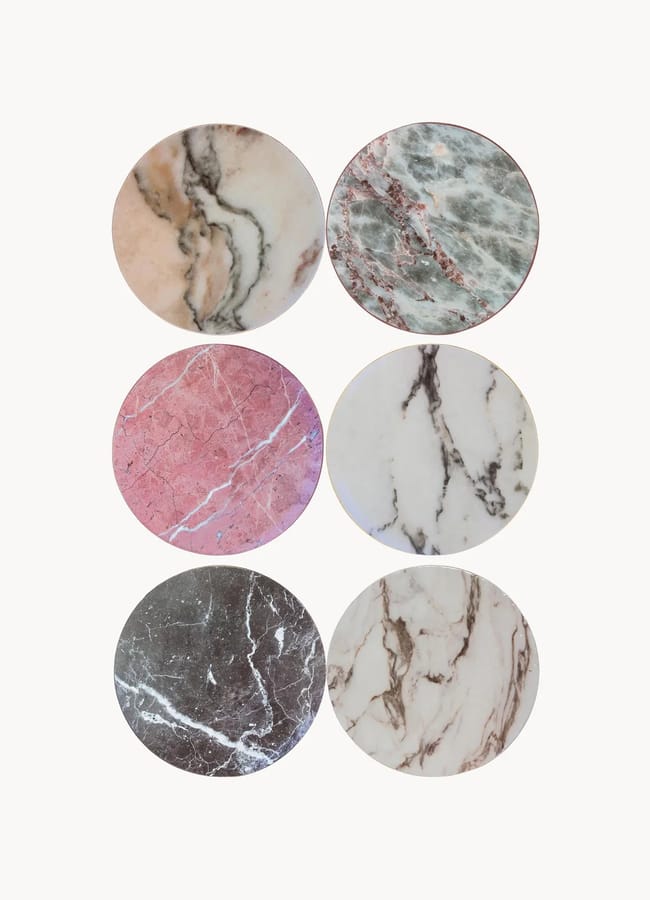 Six circular coasters in marble patterns of beige, green, pink, white, and charcoal grey, perfect for finishing your listening room interior.