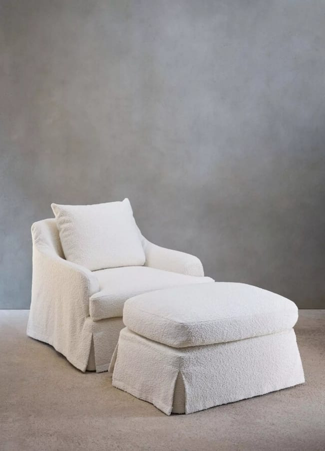 White bouclé armchair with a matching footstool.